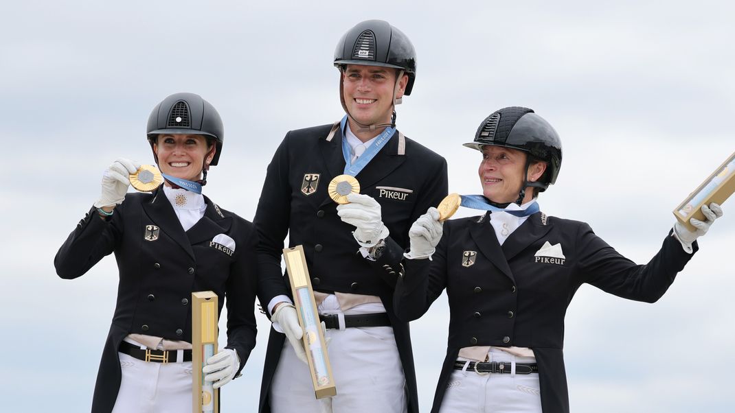 Jessica von Bredow-Werndl (l-r), Frederic Wandres und Isabell Werth jubeln bei der Siegerehrung über Gold.