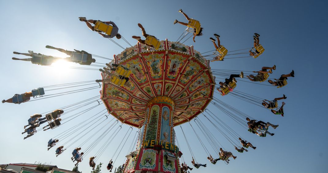 Auf dem Oktoberfest fliegen die Fahrgäste eine Runde Kettenkarussell. 