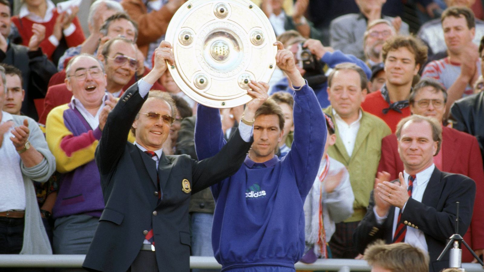 
                <strong>Franz Beckenbauer (28. Dezember 1993 bis 30. Juni 1994)</strong><br>
                Das Team Beckenbauer (li.) und Augenthaler (re.) funktionierte auch schon etwa zweieinhalb Jahre vorher, beim ersten Interims-Job von "Kaiser Franz" bei den Bayern. Nach Erich Ribbecks Entlassung sprang Beckenbauer ein und führte die Münchner in 14 Bundesliga-Spielen mit neun Siegen und zwei Unentschieden noch vom dritten Platz zum Meistertitel. Auf Beckenbauer folgte im Sommer 1994 die erste Bayern-Ära des Italieners Giovanni Trapattoni.
              