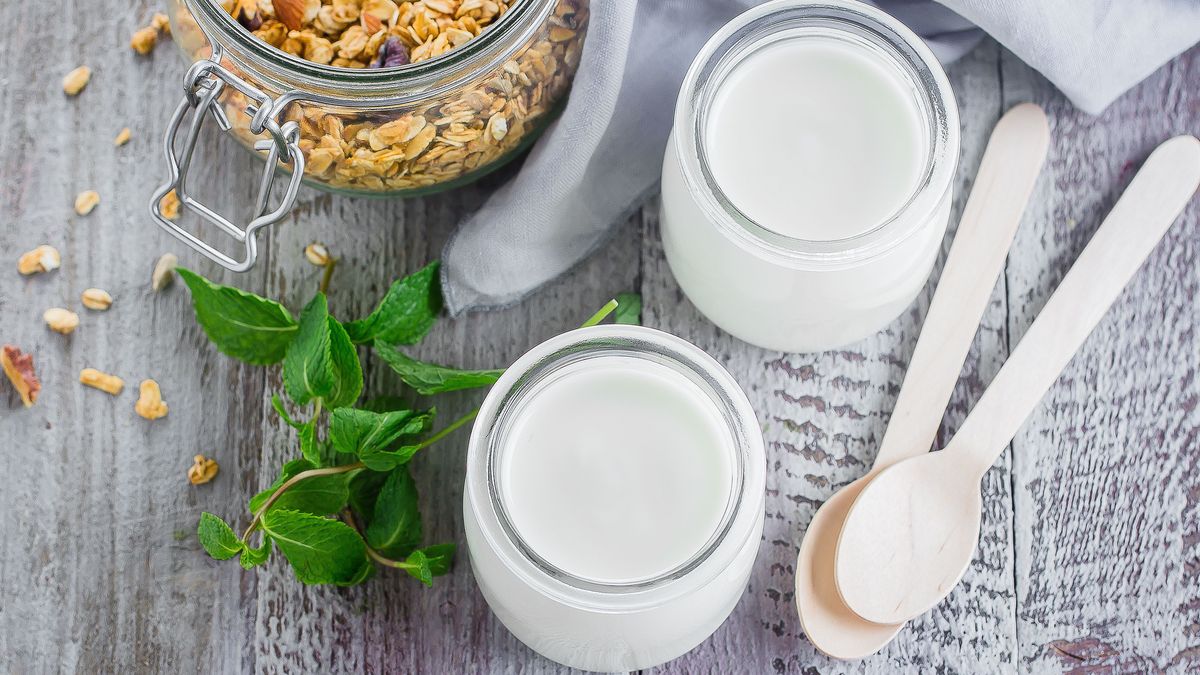 Two glass jarы with greek yogurt and jar with homemade oat granola for healthy breakfast, top view