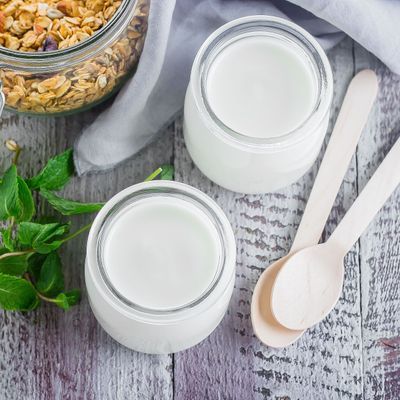 Two glass jarы with greek yogurt and jar with homemade oat granola for healthy breakfast, top view