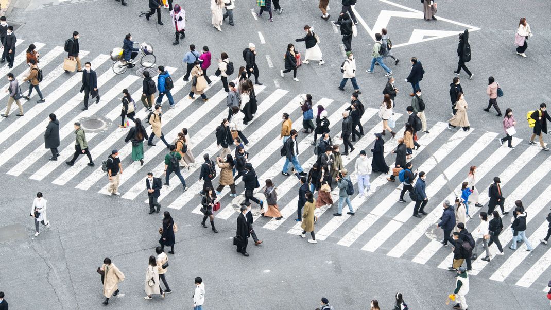 Japanische Arbeiter:innen überqueren die Shibuya-Kreuzung