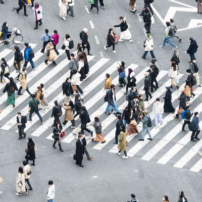 Japanische Arbeiter:innen überqueren die Shibuya-Kreuzung