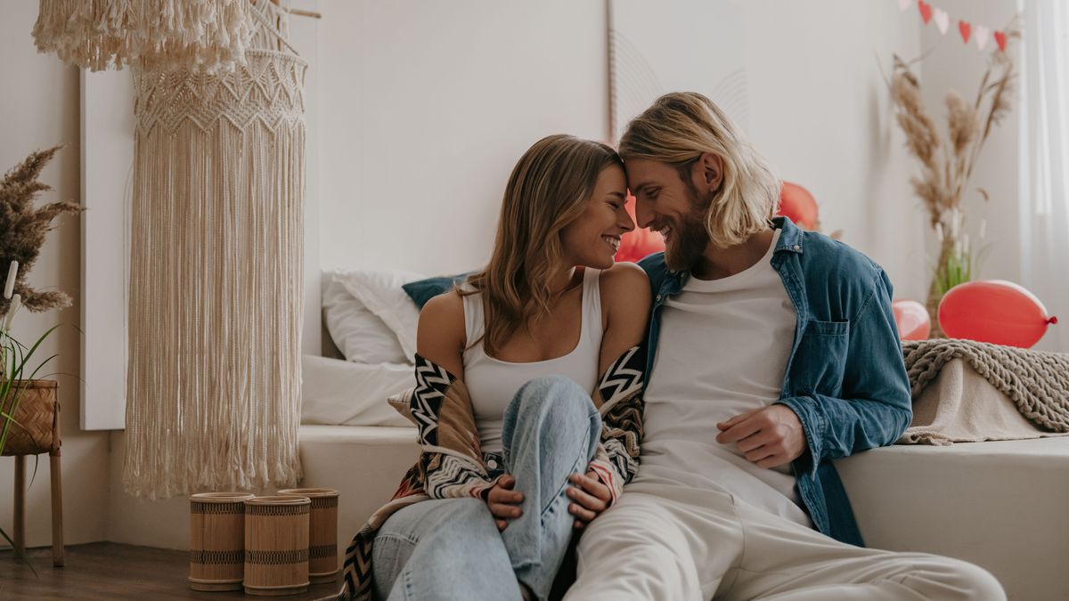 Young romantic couple embracing face to face while celebrating Valentines day at decorated cozy home