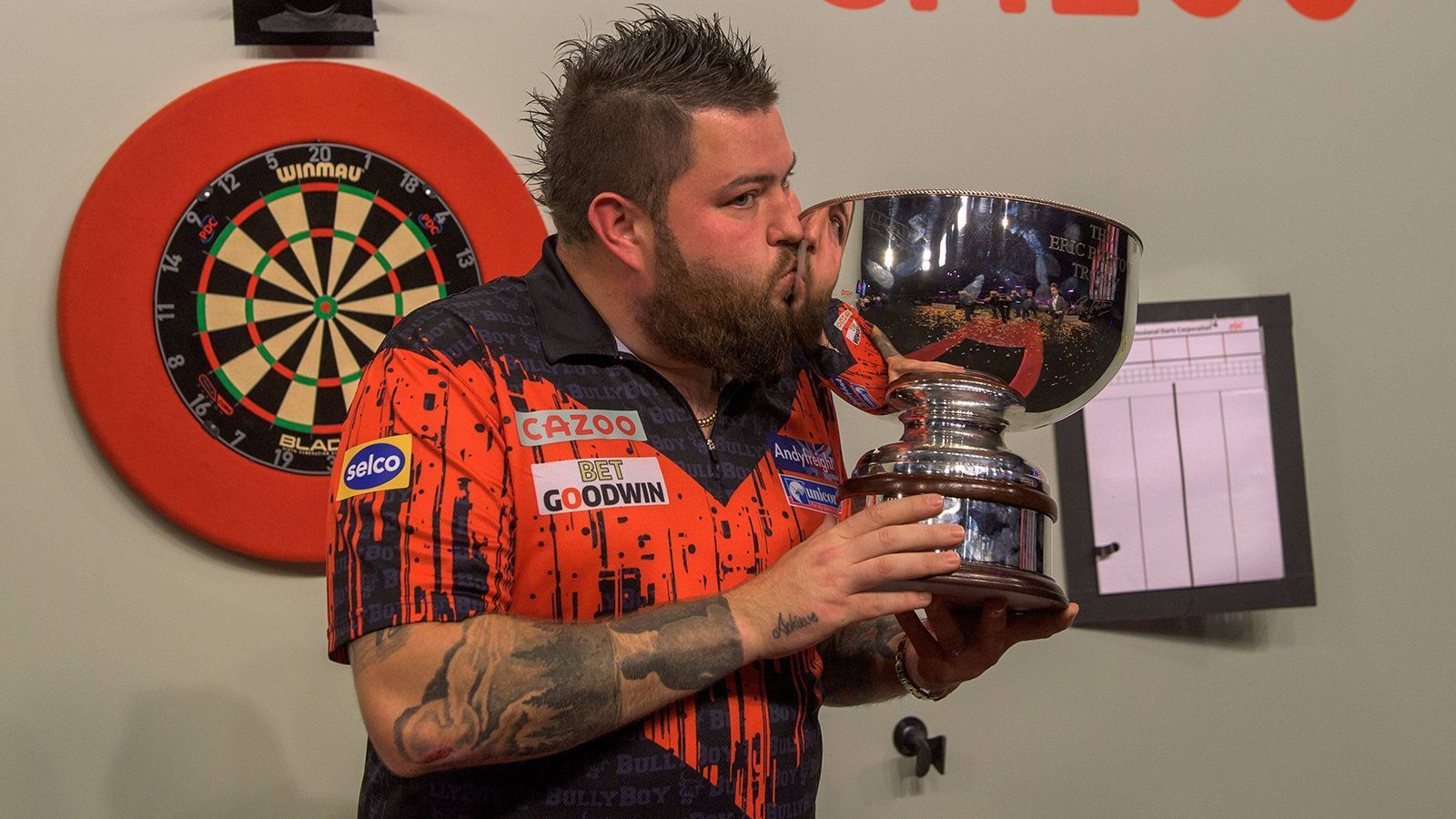 
                <strong>Michael Smith</strong><br>
                Das Warten hat endlich ein Ende! Der Knoten ist endlich geplatzt! Der Bann endlich gebrochen! Nach zuvor acht verlorenen Major-Finals gewann der "Bully Boy" Ende November, mit dem "Grand Slam of Darts", endlich sein erstes großes PDC-Turnier. Aufgrund dieses Erfolges gilt Smith bei der WM als einer der Top-Favoriten. Viele Experten gehen davon aus, dass der Engländer nun endlich befreit aufspielen kann. In seiner Karriere stand der 32-Jährige bereits zweimal im Finale, verlor jedoch gegen Michael van Gerwen (2019) und Peter Wright (2022).
              