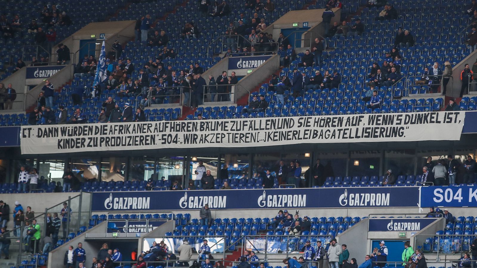 
                <strong>Drei Monate Pause</strong><br>
                Tönnies bekam dafür zurecht jede Menge Kritik ab, ihm wurde Rassismus vorgeworfen, sogar sehr viele Schalker Fans sahen das so und wandten sich ab, protestierten, forderten den Rücktritt des allmächtigen Bosses. Der Klub? Der Verband? Hauten dem Schalke-Boss ein bisschen auf die Finger. Er hatte sich ja schließlich entschuldigt. Drei Monate musste er sein Amt ruhen lassen, dann ging es weiter, als ob nichts gewesen wäre.
              