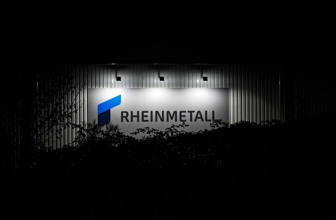 Das beleuchtete Logo und der Schriftzug der Rüstungsfirma Rheinmetall hängen an einer Produktionshalle. (Symbolbild)