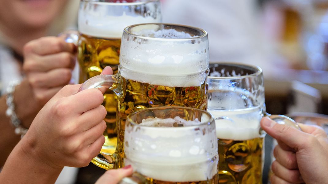 Besucher stoßen auf dem Münchner Oktoberfest mit Bier an.