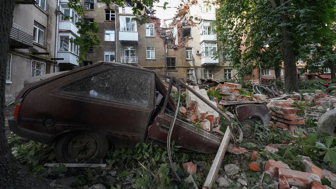 Sumy: Ein Autowrack ist nach einem Angriff vor einem beschädigten Wohnhaus zu sehen. (Symbolbild)