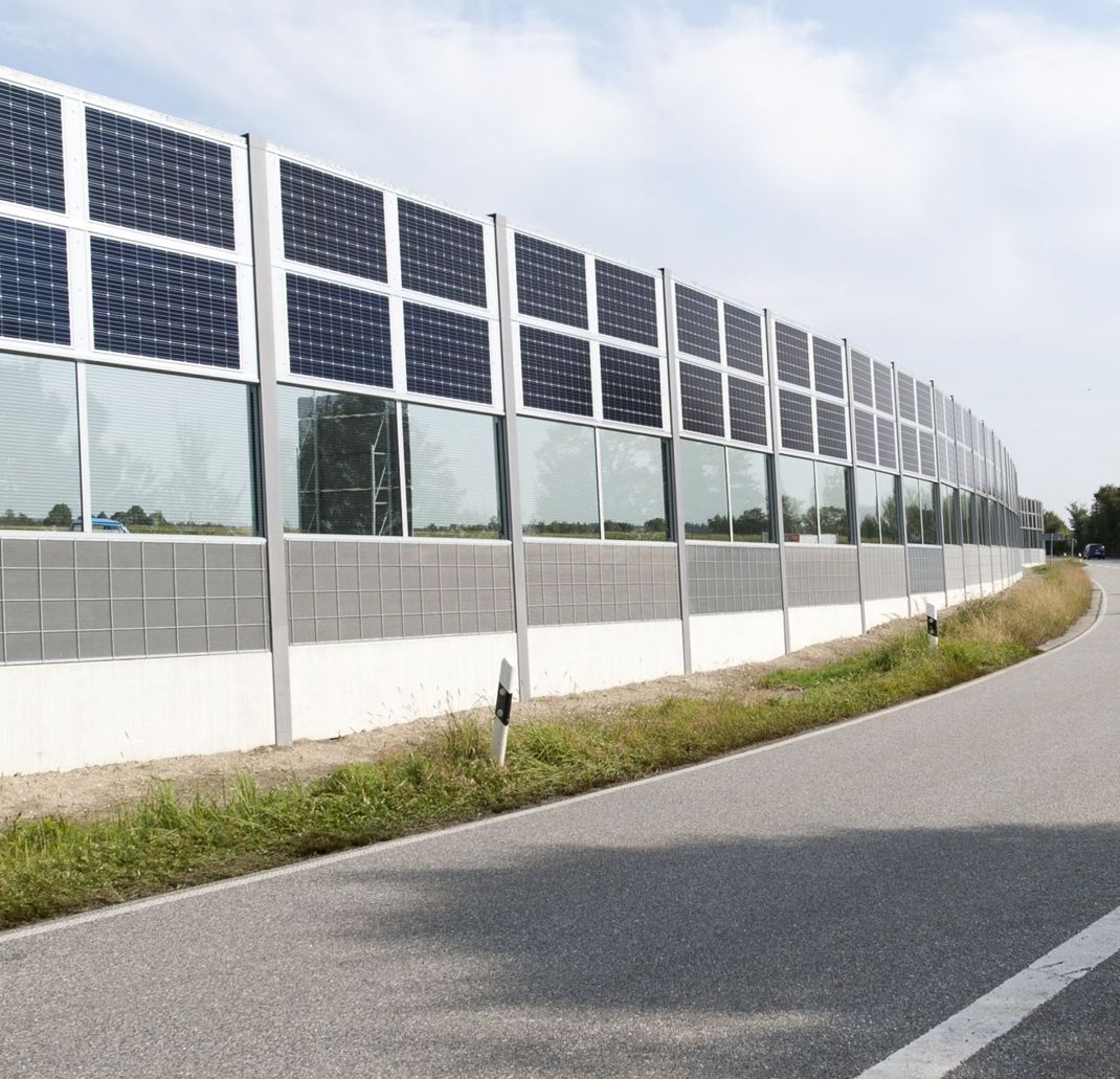 Eine massive Lärmschutzwand mit teiltransparenter Ausführung und Standard-PV-Modulen. PV steht für Photo-voltaik. Dieses Beipiel zeigt: Auch bestehende Schutzwände können solartechnisch nachgerüstet werden.