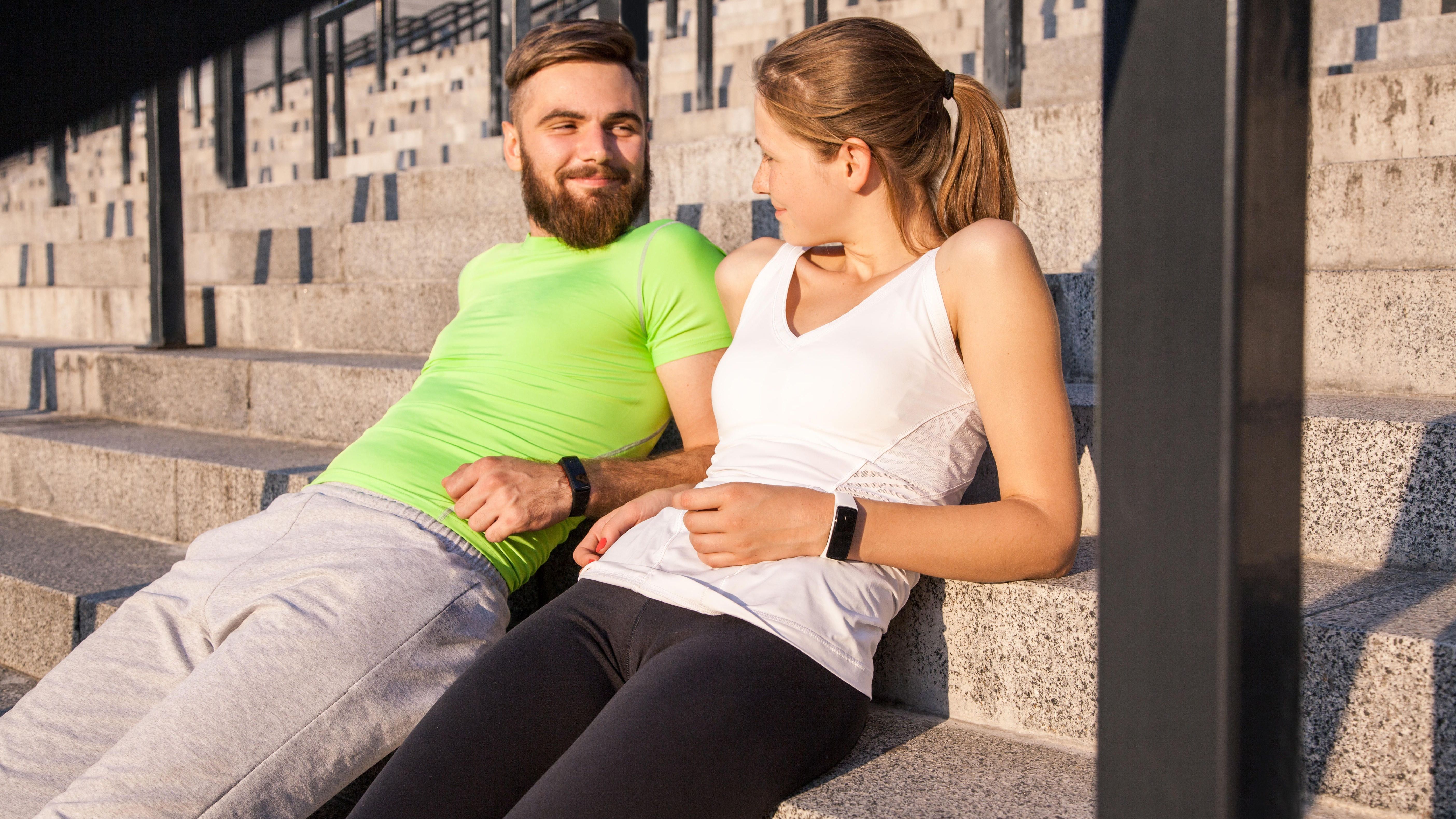 Young sporty couple are resting and check their fitness watch together. sport and technology concepts. || Modellfreigabe vorhanden