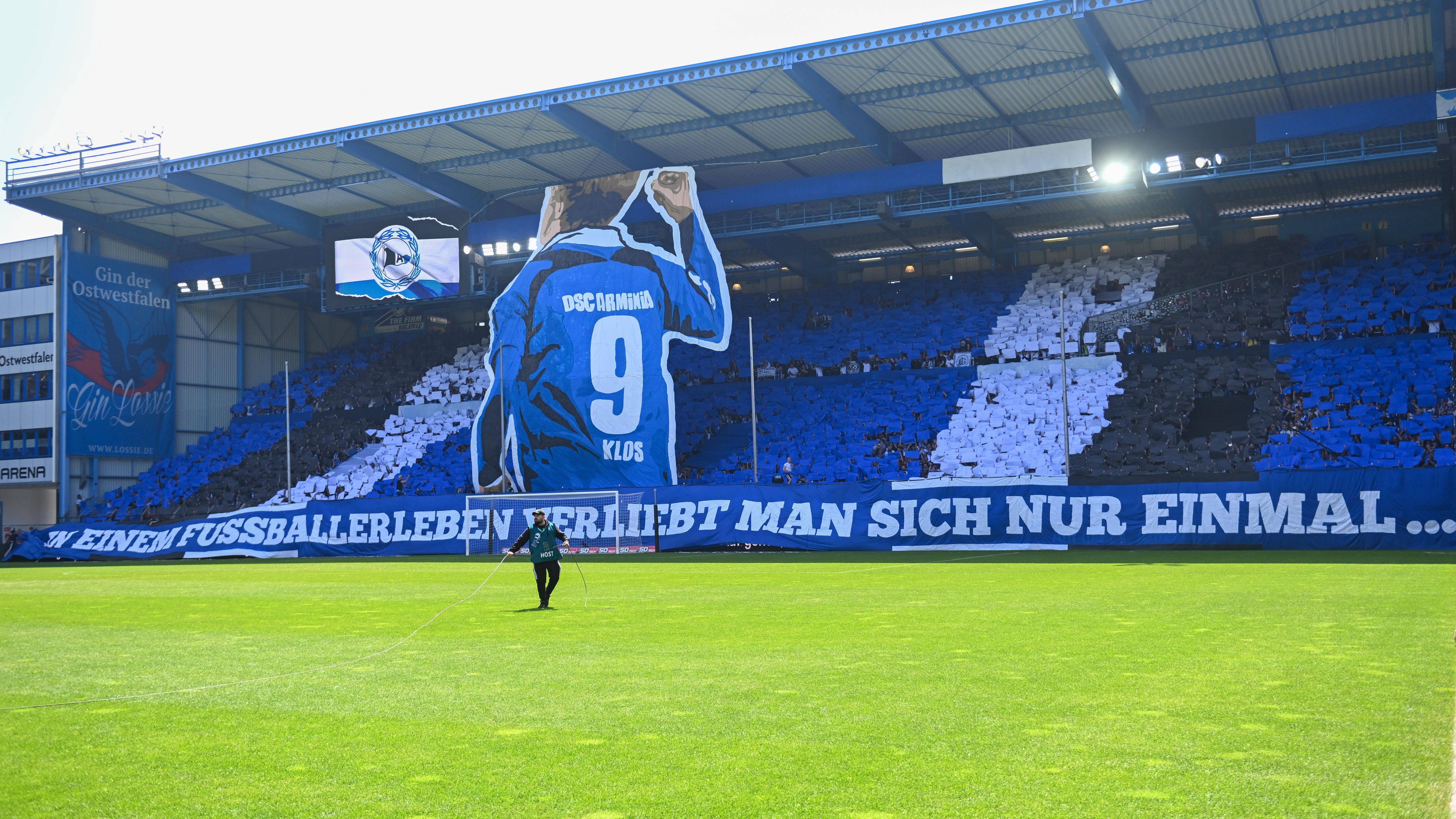 <strong>Arminia-Fans verabschieden Fabian Klos</strong><br>Mitt 36 Jahren soll Schluss sein für Fabian Klos. Anlässlich seines letzten Heimspiels lief Arminia Bielefeld gegen den Halleschen FC mit einem Sondertrikot namens "Fabis letztes Hemd" auf. Die Fans des Drittligisten bedankten sich vor Anpfiff für 13 Jahre Loyalität und nahmen Bezug auf ein Zitat des Angreifers: "In einem Fußballerleben verliebt man sich nur einmal. Bei Arminia und mir ist das so."