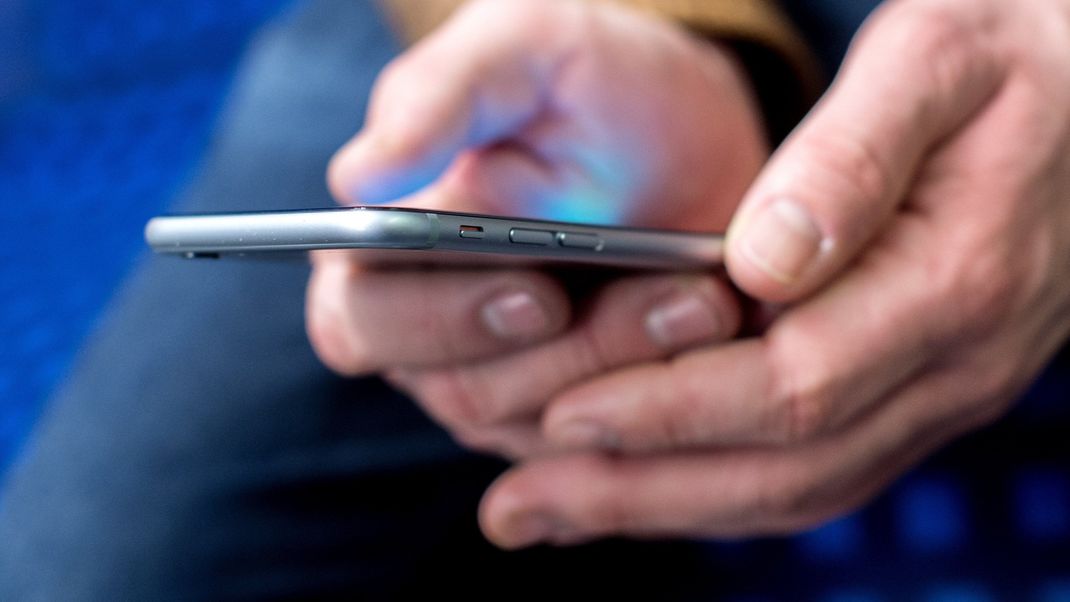 Archivbild: Ein junger Mann sitzt in einer S-Bahn und benutzt dabei sein Smartphone. 