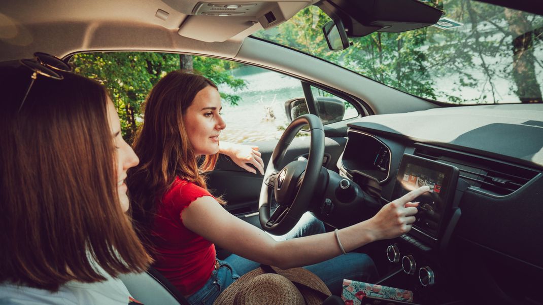 Two young girls listening to good music while driving in car, enjoy summer road trip in nature. || Modellfreigabe vorhanden