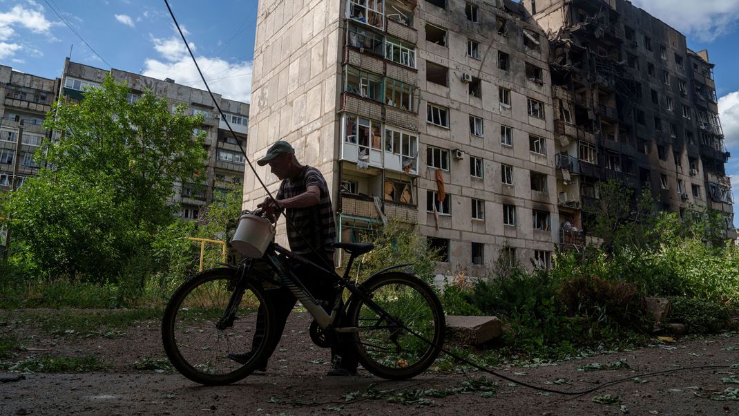 Ein Mann schiebt sein Fahrrad vor einem Wohnhaus in Torezk, das durch einen russischen Luftangriff zerstört wurde.