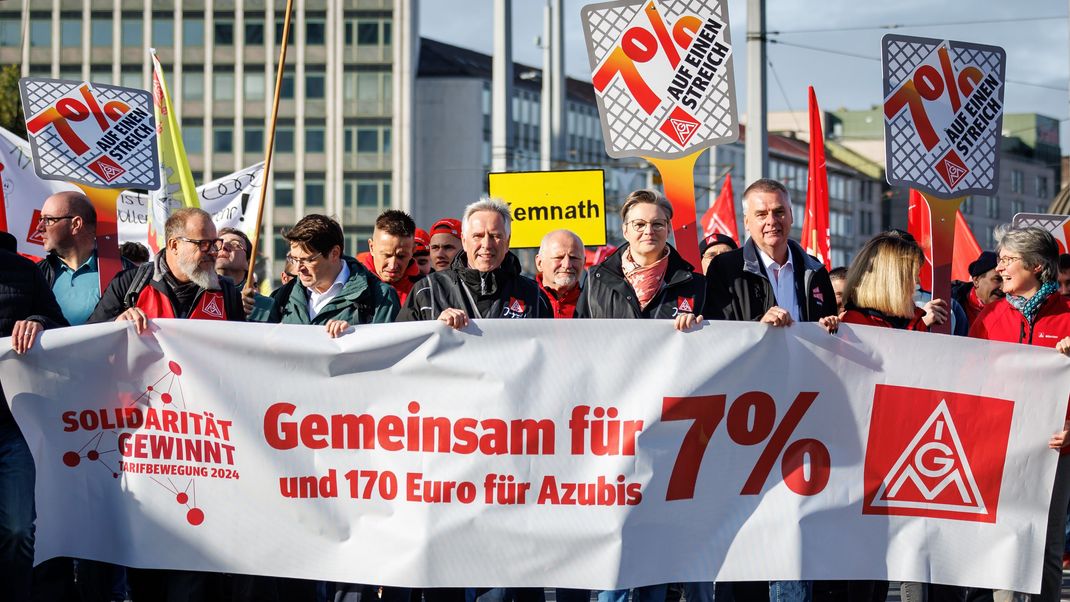 Horst Ott (M), Bezirksleiter und Verhandlungsführer IG Metall Bayern, läuft hinter einem Banner mit der Aufschrift «Gemeinsam für 7 Prozent»