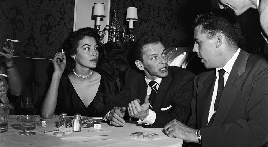 
                <strong>Otto Graham</strong><br>
                Otto Graham (re.), hier mit Frank und Nancy Sinatra zu sehen, galt zu seiner Zeit als der beste Quarterback des Landes. Nachdem er im Jahr 1954 die NFL-Championship gewann, beendete er seine Karriere. Doch der Hunger nach Trophäen trieb ihn nur eine Saison später wieder auf das Feld. Eine gute Entscheidung, denn Graham sicherte sich auch 1955 mit den Cleveland Browns die NFL-Trophäe. 
              