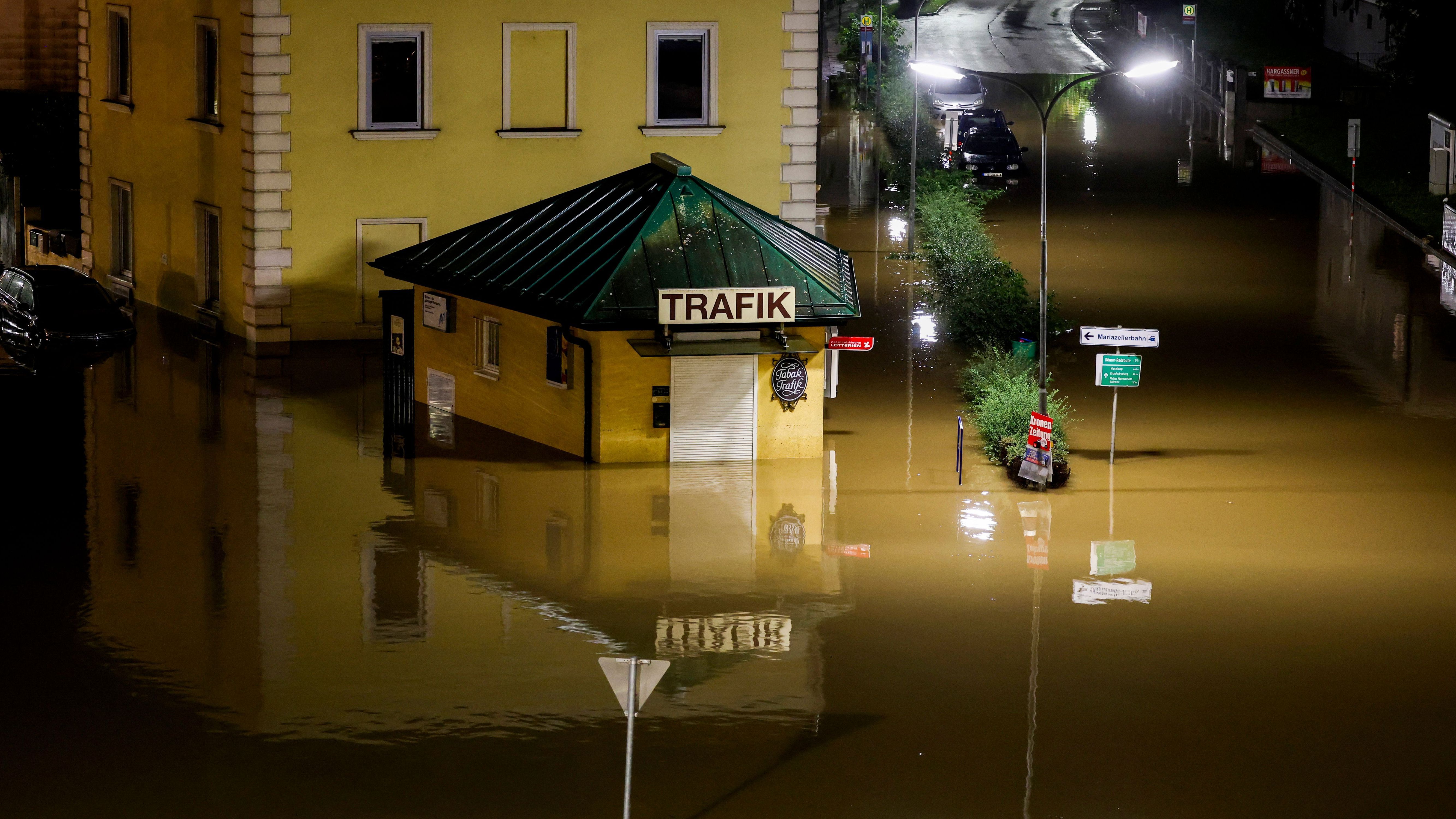 Am Bahnhof St. Pölten Alpenbahnhof in Österreich stehen ein Kiosk und mehrere Autos nach Regenfällen im Hochwasser. 