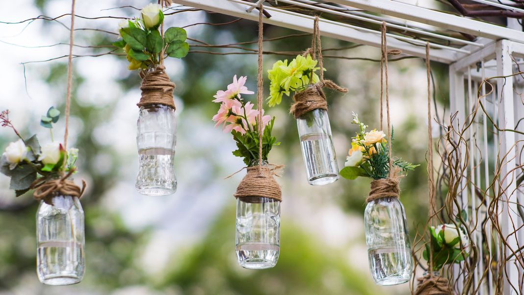 Minimalistisch und doch wunderschön: Eine hängende Blumen-Girlande aus Glasflaschen.