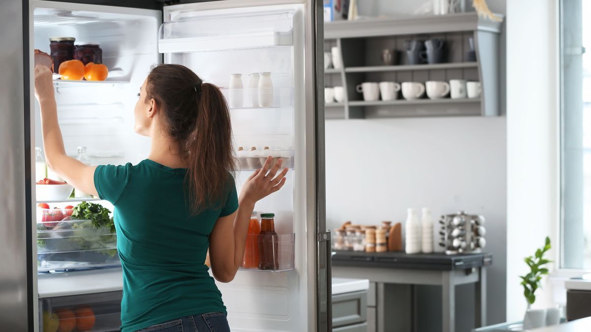 Woman taking food out of fridge at home