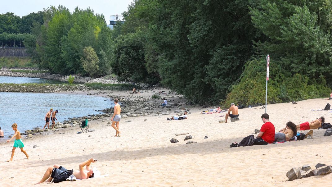 Düsseldorf: Menschen sitzen am Paradiesstrand am Rhein. In der nordrhein-westfälischen Landeshauptstadt gilt ab heute ein Badeverbot im Rhein.