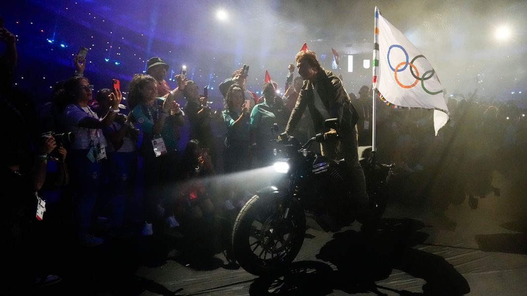 Unten angekommen schnappte sich Cruise die olympische Fahne von Los Angeles und jagte auf einem Motorrad hinaus.