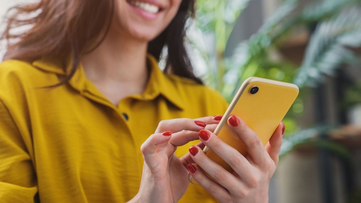 Abgeschnittenes Bild von glücklichen Mädchen mit Smartphone-Gerät beim Chillen zu Hause