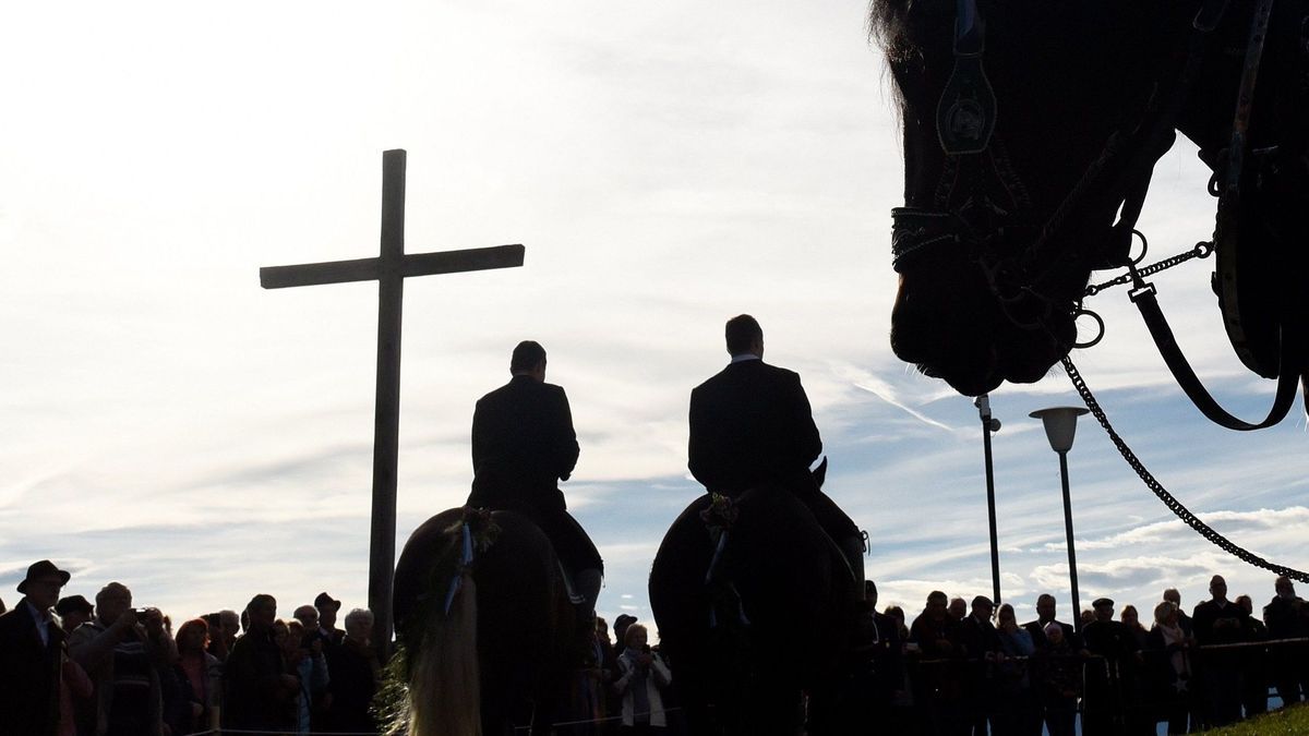 Männer reiten bei der traditionellen Leonhardifahrt an einem Kreuz vorbei. Bei einer traditionellen Prozession in Schwaben bricht ein Teil einer Kutsche. 