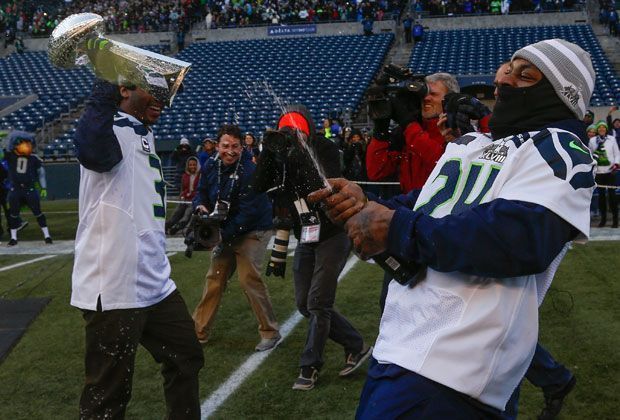 
                <strong>Auf die Flaschen</strong><br>
                Marshawn Lynch (r.) und Russell Wilson (l.) mit geteilten Aufgaben: Der eine sichert die Vince Lombardi Trophy, während sich der andere um die kühlen Getränke kümmert.
              