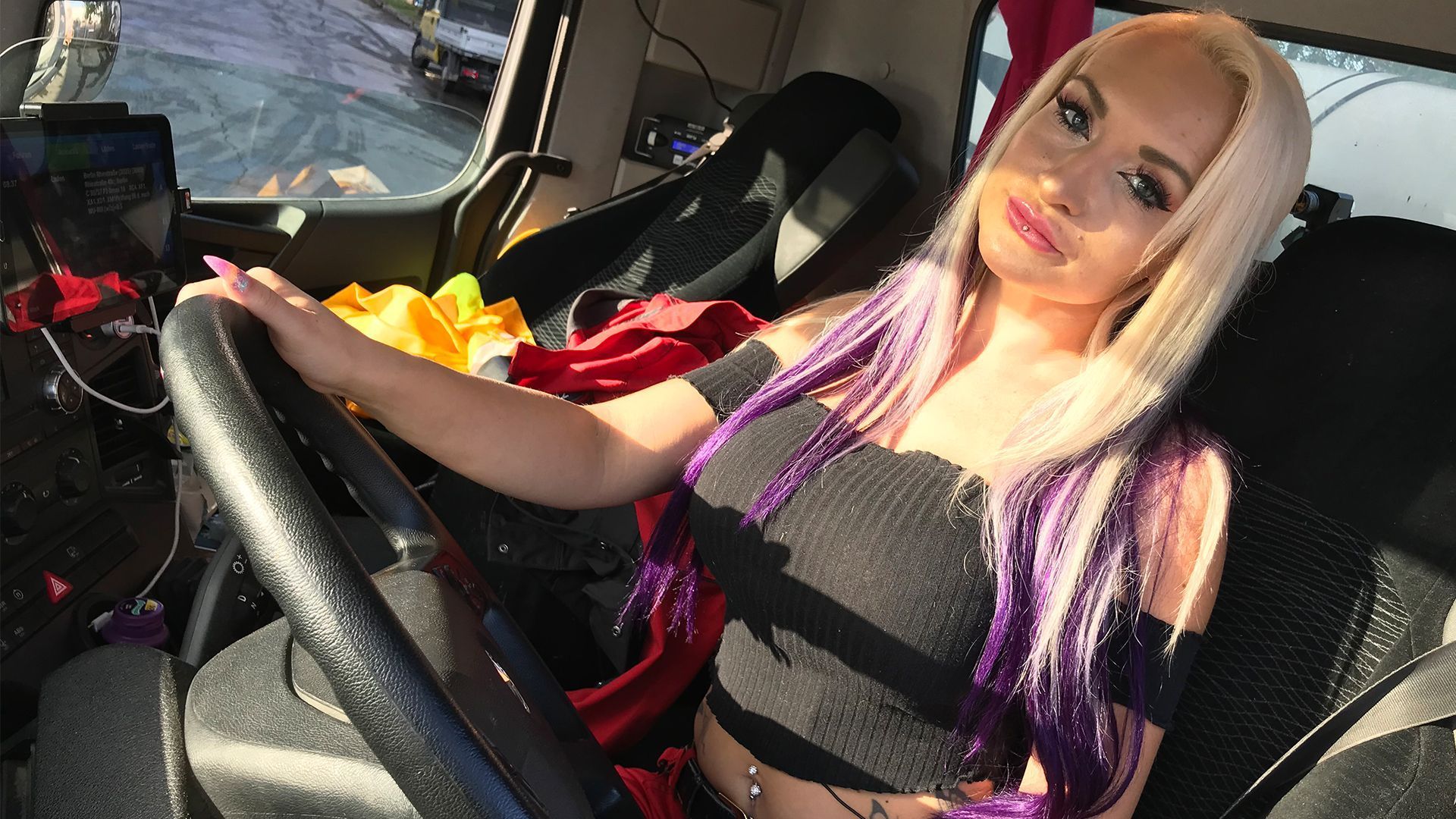 "Trucker Babe" Sarah sitzt am Steuer ihres Betonmischers und lächelt in die Kamera.