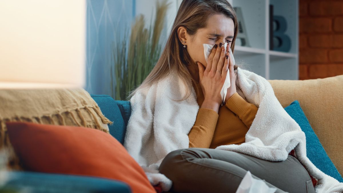 Woman with cold and flu blowing her nose