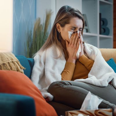 Woman with cold and flu blowing her nose