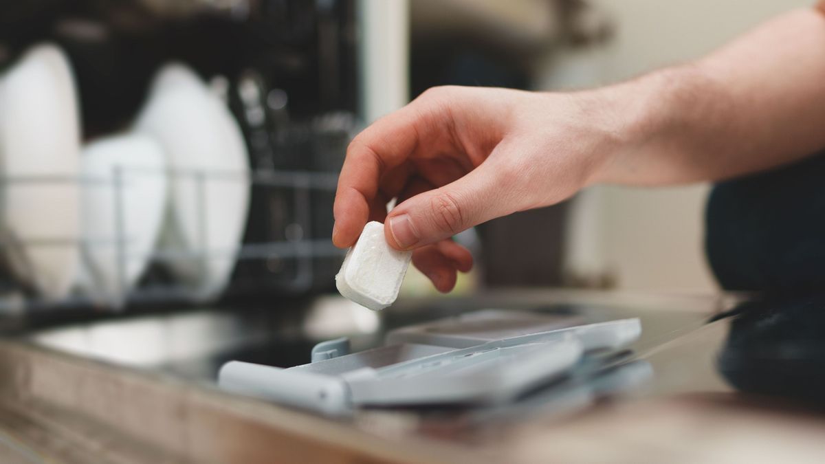 Man putting detergent tablet into dishwasher.