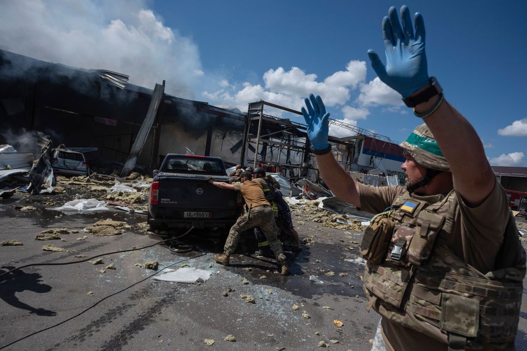 Rettungskräfte und Soldaten schieben ein beschädigtes Auto, nachdem eine russische Rakete einen Supermarkt in der Region Donezk getroffen hat. Nach Angaben des Innenministeriums brach ein Brand auf gut 1.000 Quadratmetern aus. Kostjantyniwka ist nur etwas mehr als zehn Kilometer von der Frontlinie zwischen ukrainischen und russischen Truppen entfernt. 