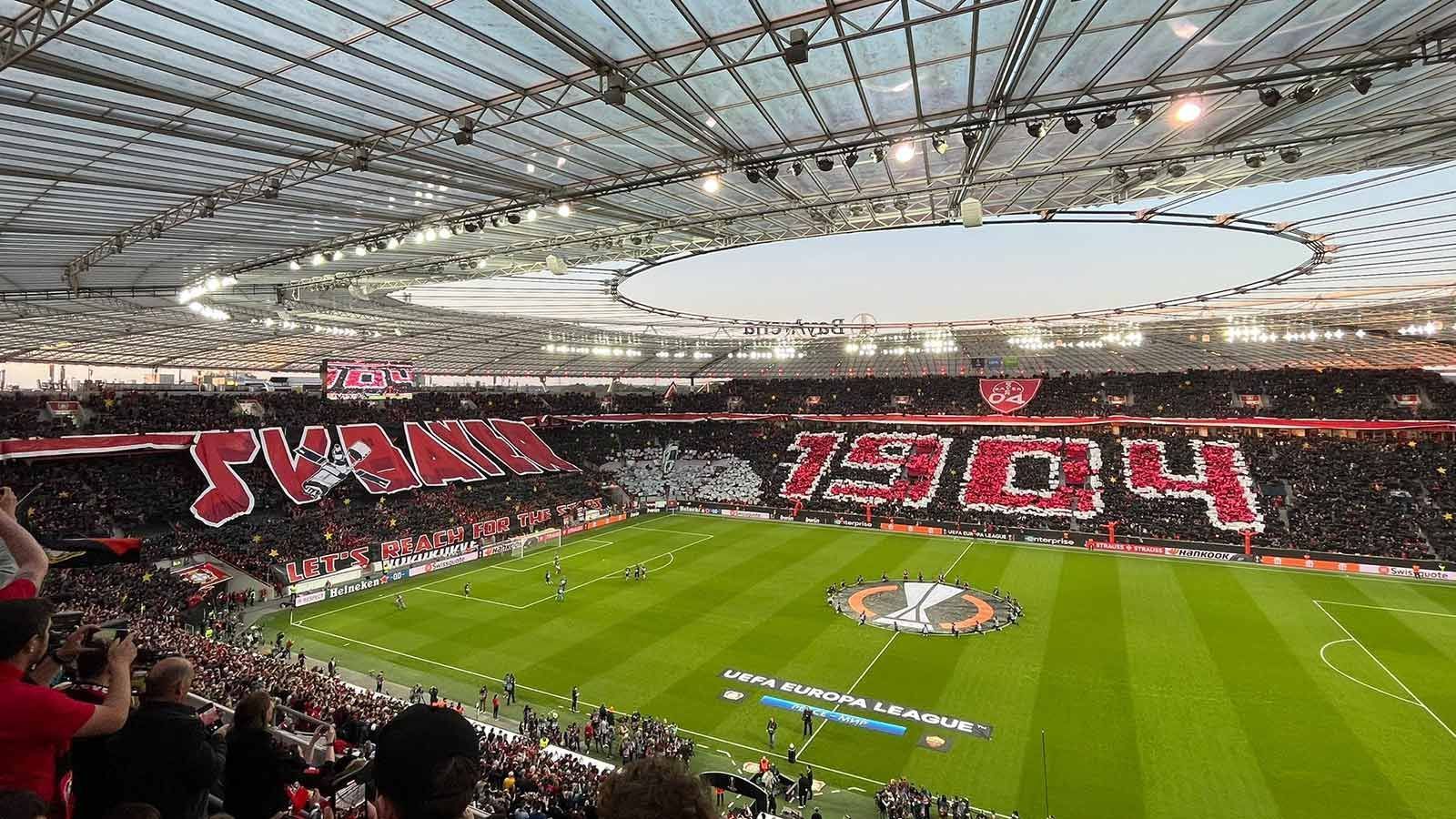
                <strong>Bayer 04 Leverkusen - Fans wollen gegen AS Rom nach den Sternen greifen</strong><br>
                Nach einem 0:1 aus dem Hinspiel hoffen die Fans von Bayer 04 Leverkusen vor dem Rückspiel im Halbfinale der Europa League immer noch auf ein Weiterkommen. Das Motto: "Lasst uns nach den Sternen greifen". Zum Einlauf spielte die Stadionregie zudem den "Imperial March" aus "Star Wars". Ein stimmungsvoller Auftakt für eine europäische Nacht.
              