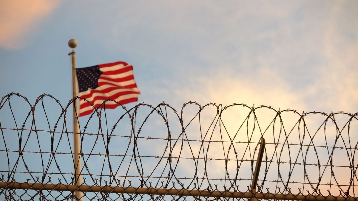 Archivaufnahme, 16. Oktober 2018, Kuba, Guantanamo Bay: Eine US-amerikanische Flagge weht hinter dem Stacheldrahtzaun im berüchtigten Gefangenenlager der US Navy in der Guantánamo-Bucht