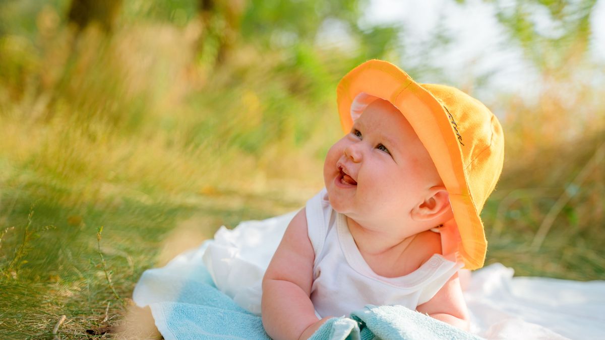 Funny baby toddler in a panama hat is relaxing on the beach outdoors in summer