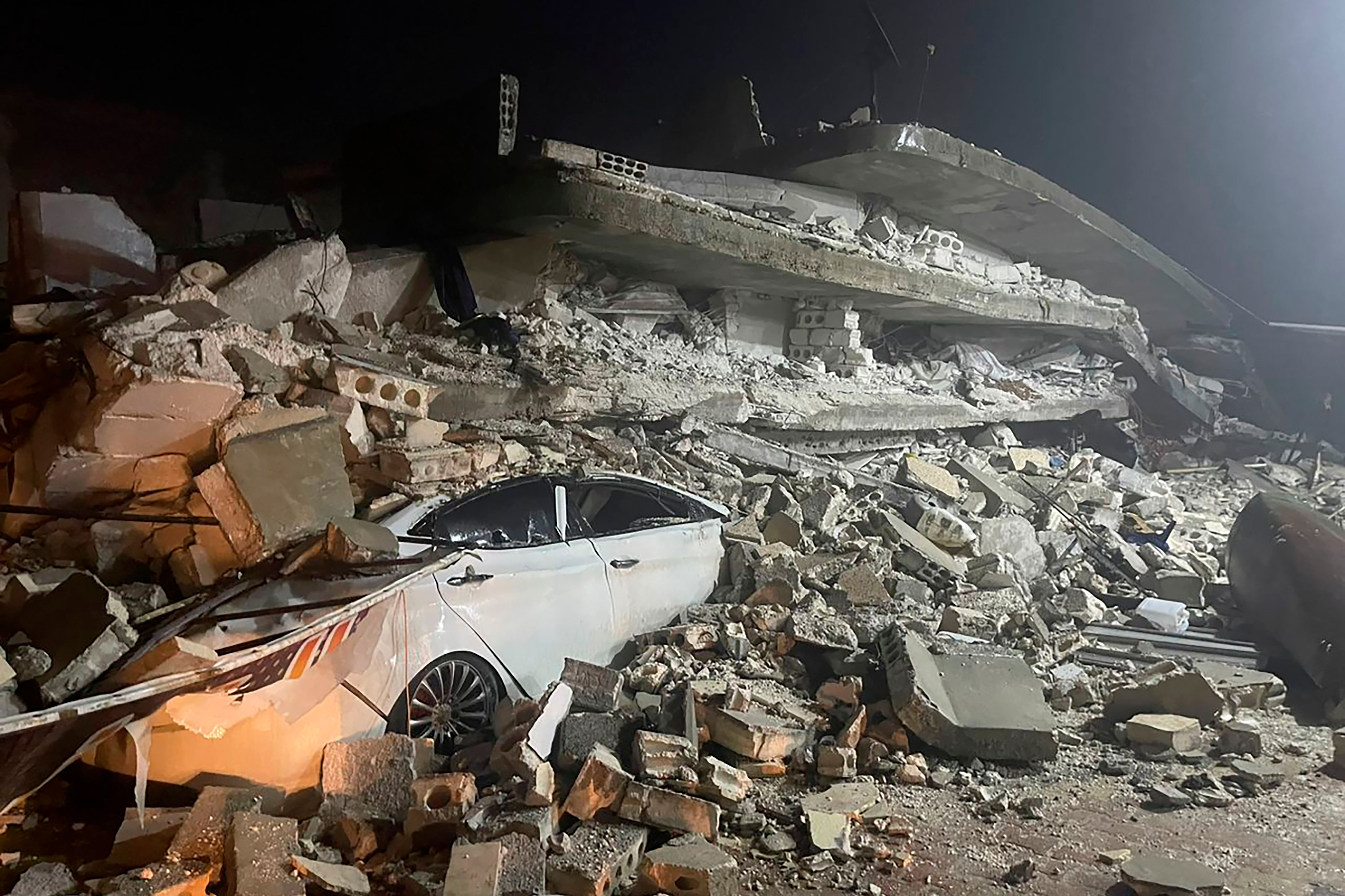 Ein Auto ist unter den Trümmern eines eingestürzten Gebäudes in der Stadt Azmarin in der nordsyrischen Provinz Idlib zu sehen.