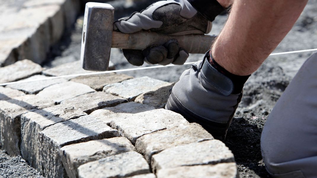 Heimwerker pflastert mit dem Baustoff Granit einen Weg.