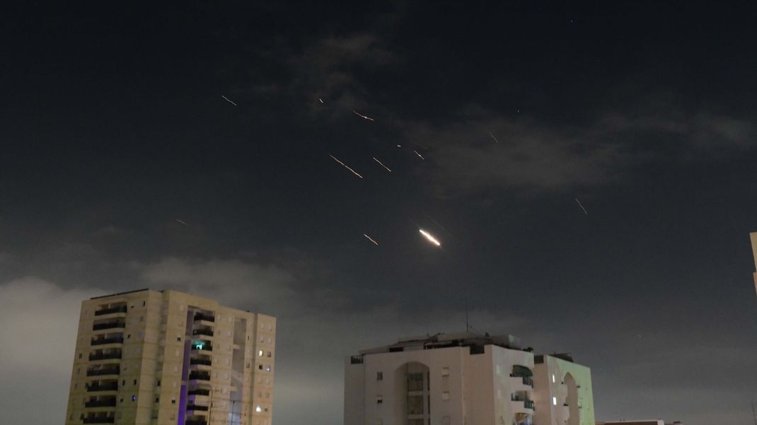 Flammen von Explosionen erscheinen am Himmel über Tel Aviv, während Israels Raketenabwehrsystem Raketen und Drohnen aus dem Iran abfängt. Der Iran hat erstmals Israel direkt angegriffen.