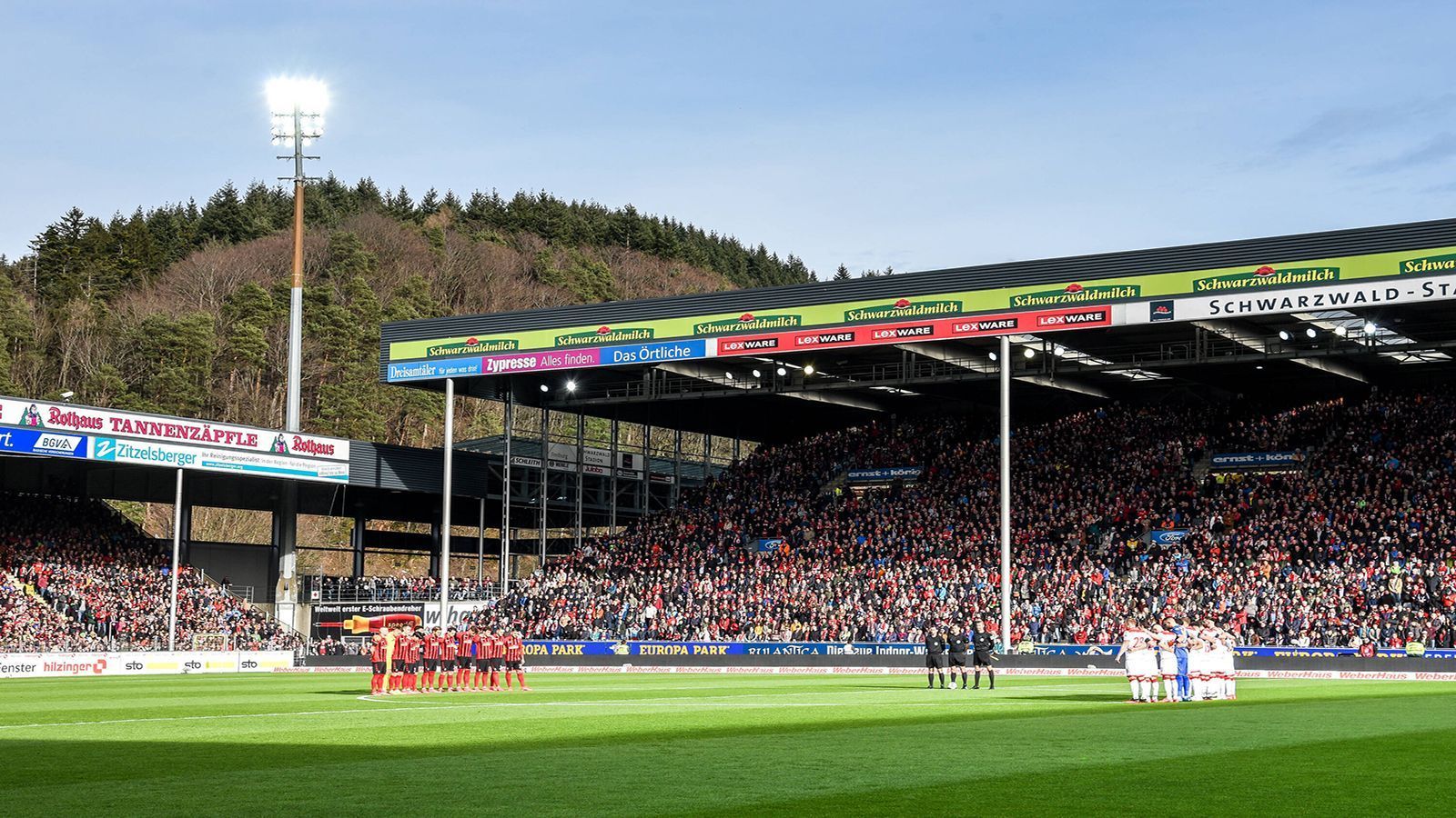 
                <strong>SC Freiburg: Unebener Platz und das kürzeste Spielfeld der Liga</strong><br>
                Für Verwunderung sorgt im badischen Schwarzwald-Stadion vor allem der Rasen. Von Tor zu Tor hat das Freiburger Grün ein Gefälle von fast einem Meter. Außerdem spielt der Sportclub auf dem kürzesten Spielfeld der Liga. Passend zur natürlichen Umgebung im Schwarzwald ist das Dach mit Solarmodulen versehen. Außerdem gibt es kaum Parkplätze in der direkten Nähe der Arena.
              