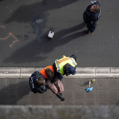 Ein Klimaaktivist wird von zwei Polizisten in Berlin von der Fahrbahn der A100 getragen.