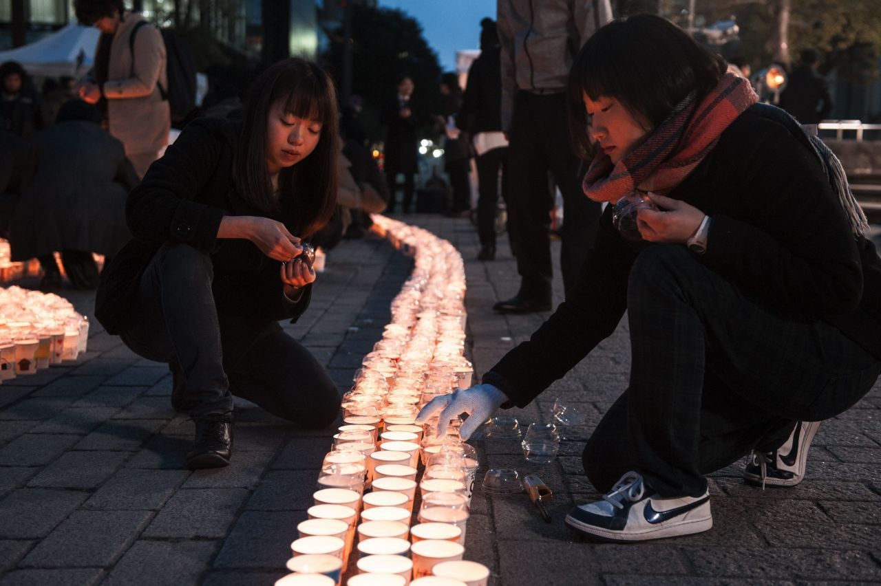 Frauen zünden 5 Jahre nach der Naturkatastrophe Kerzen zum Gedenken an. Durch das Erdbeben und den Tsunami starben über 15.000 Menschen, mehr als 6.000 wurden verletzt.