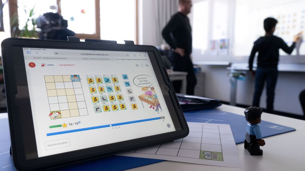 Ein Lehrer und ein Junge einer Deutschklasse stehen an der Tafel.