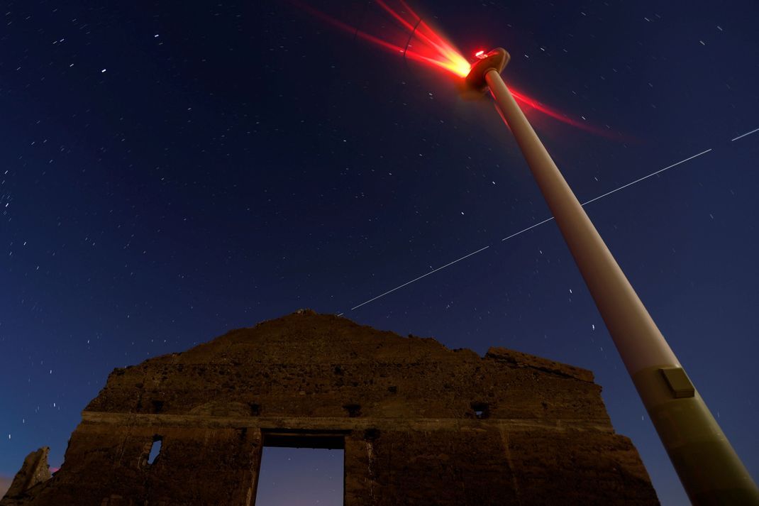 Die Internationale Raumstation ISS hinterlässt eine Leuchtspur im Himmel über einer Windturbine auf Gran Canaria.
