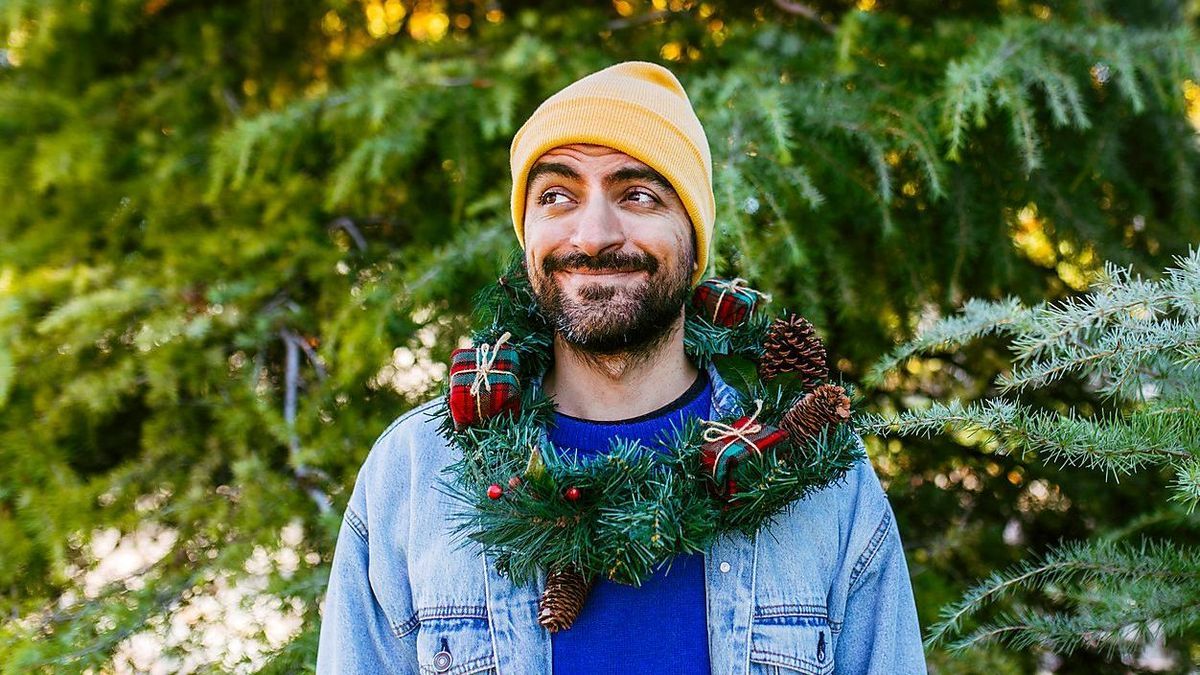 Smiling man wearing Christmas wreath around neck