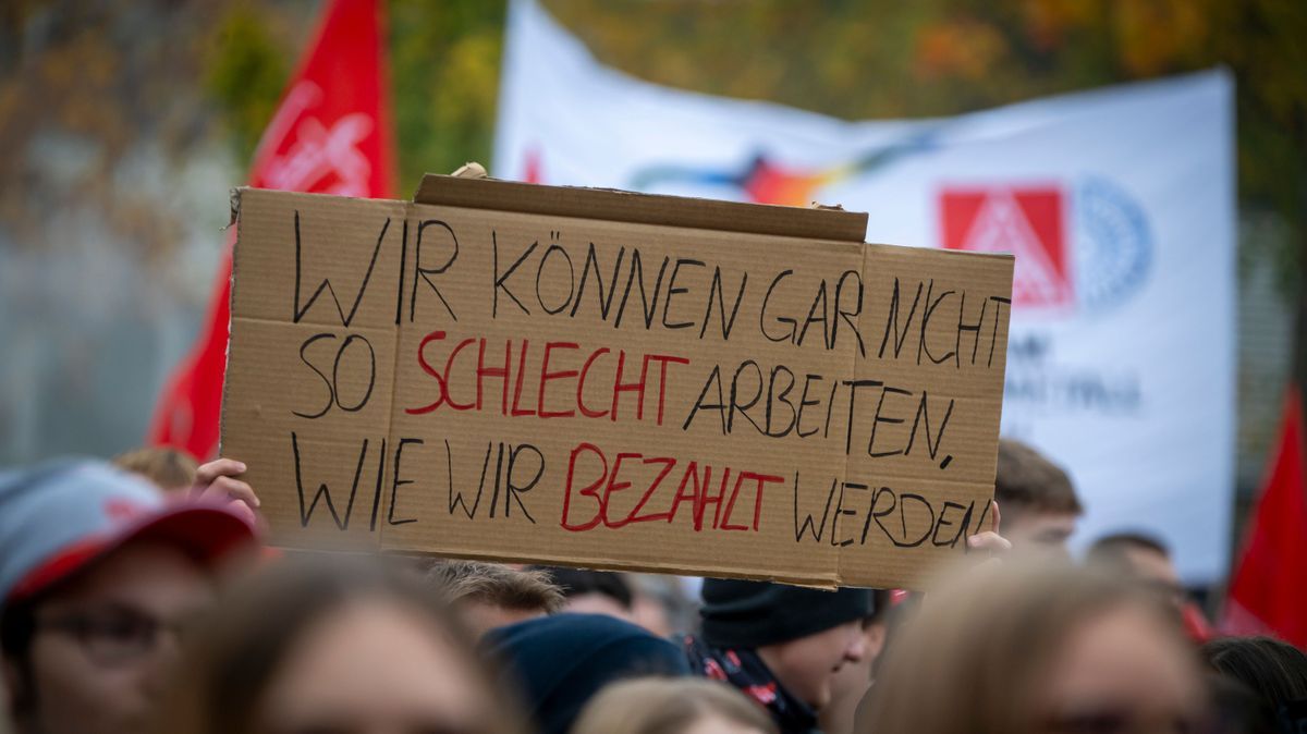 Auszubildende demonstrieren bei einem Warnstreik mit einem Plakat.