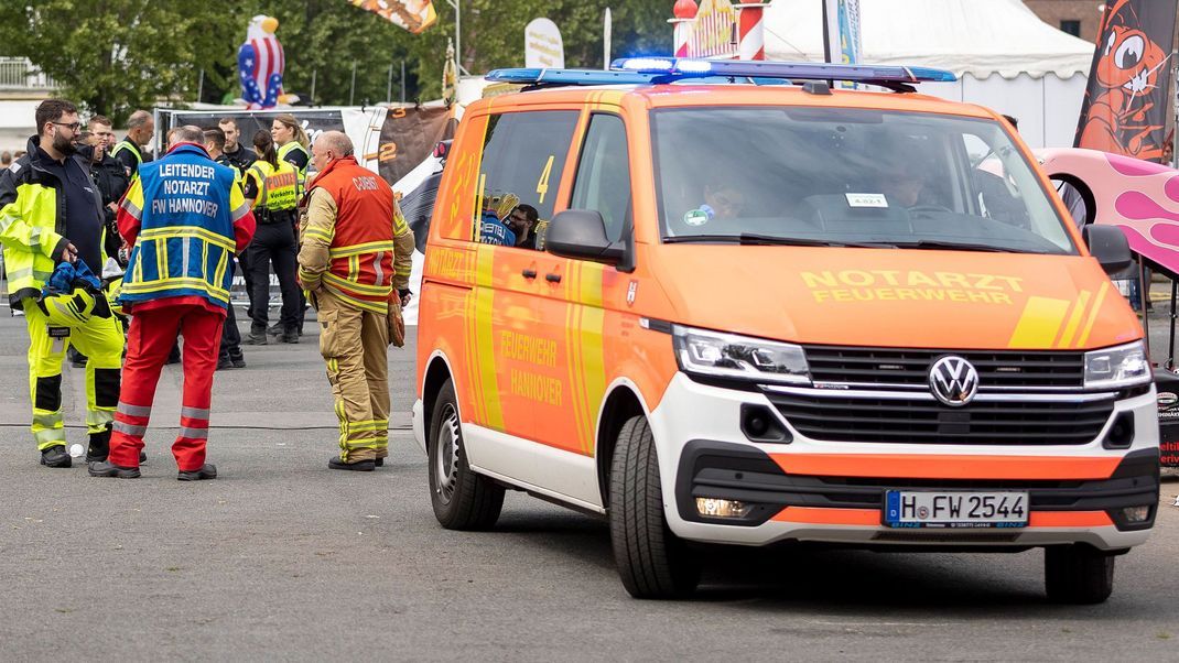 Einsatzkräfte stehen auf dem Schützenplatz neben einem Notarztwagen der Feuerwehr.