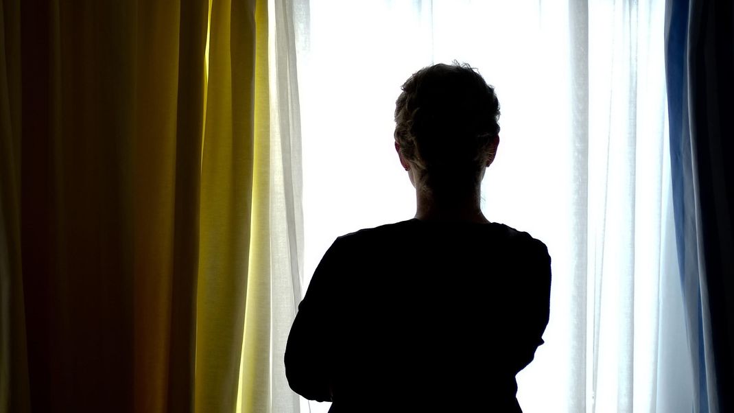 Eine junge Frau steht in einem Zimmer eines Frauenhauses. 