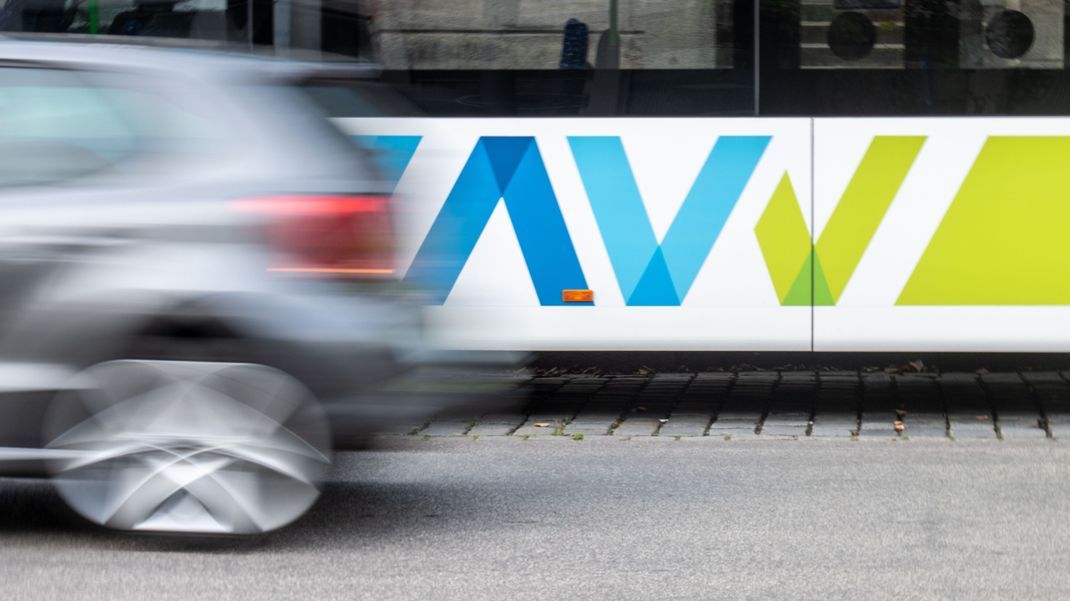 Ein Auto fährt an einem Bus mit dem Logo des Augsburger Verkehrsverbunds (AVV) vorbei.